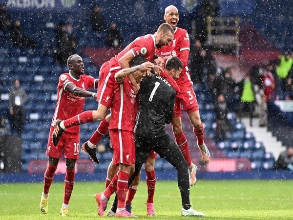 Alisson Becker disambut oleh rekan-rekan setimnya usai mencetak gol kemenangan Liverpool atas West Brom Minggu (16/5) malam / via Getty Images