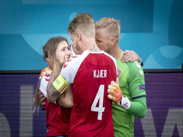 Kasper Schmeichel dan Simon Kjaer berusaha menenangkan kekasih Christian Eriksen usai nama terakhir kolaps di laga Denmark vs Finlandia (12/6) / via Getty Images
