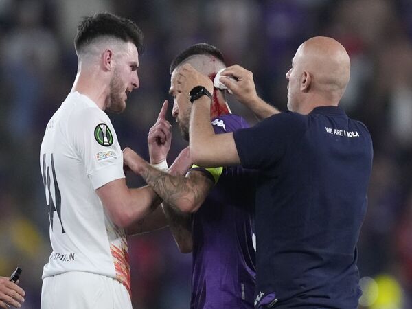 Cristiano Biraghi harus dibantu oleh Declan Rice dan staf medis Fiorentina, usai dilempari benda keras oleh suporter West Ham di final UEFA Conference League dini hari tadi (8/6) / via Getty Images